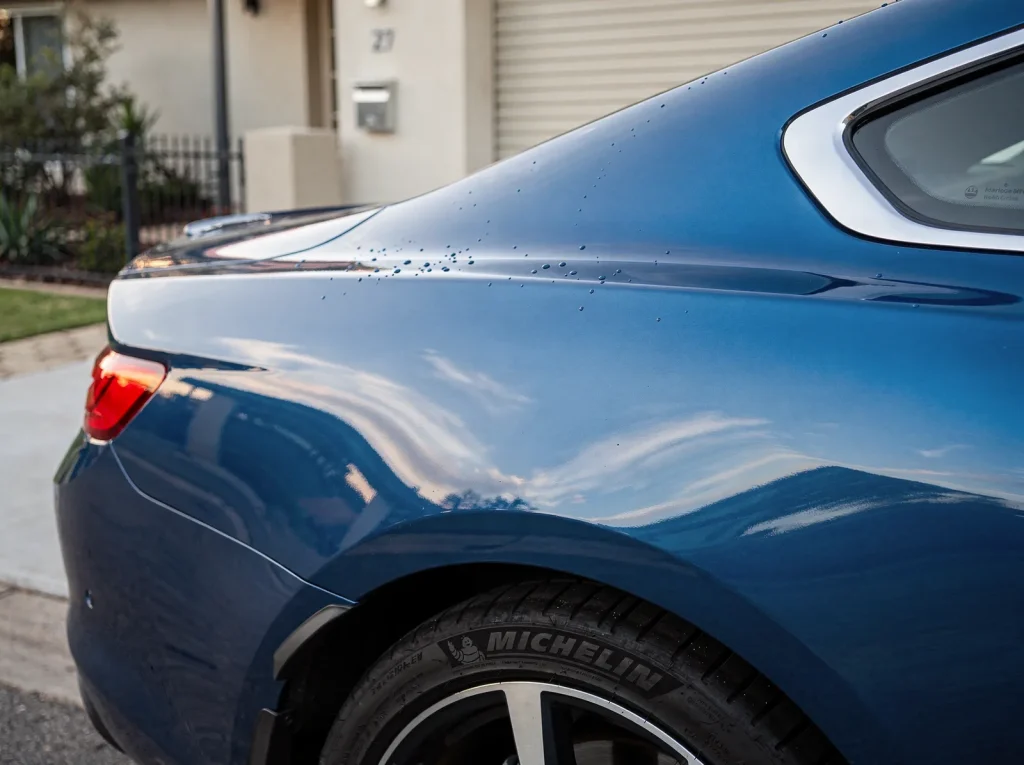 Freshly detailed metallic-blue coupe quarter-panel with mirror-like clear-coat and polished chrome in O'Connor.