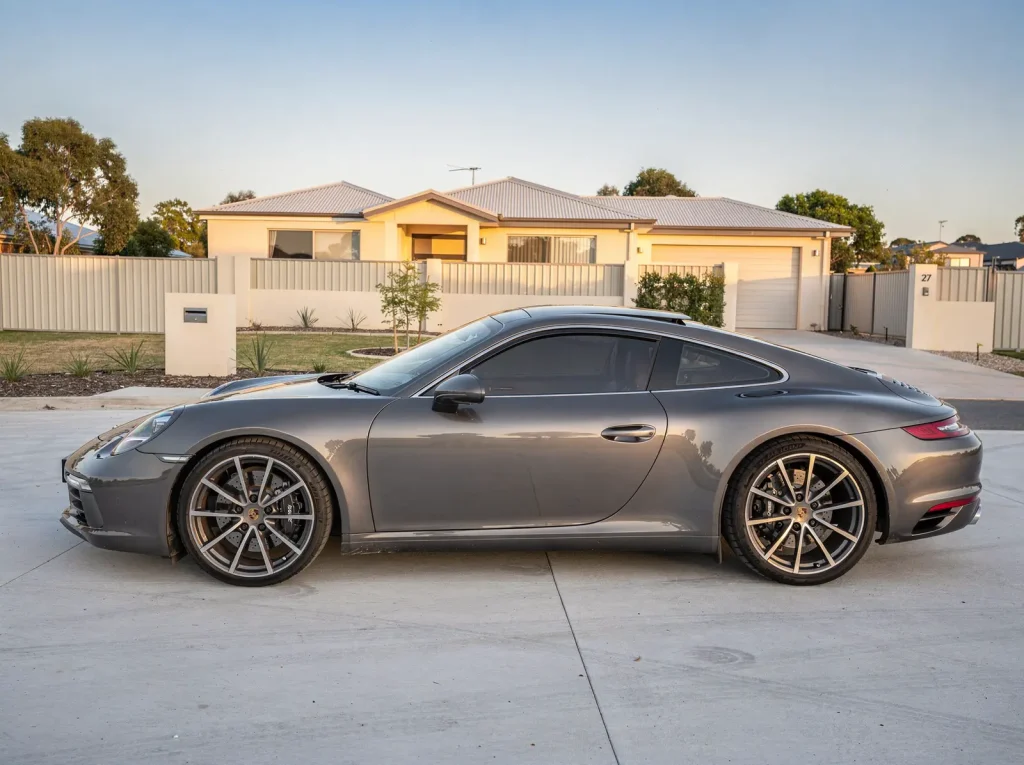 Freshly detailed metallic-grey Porsche 911 gleaming on a spotless O'Connor forecourt.