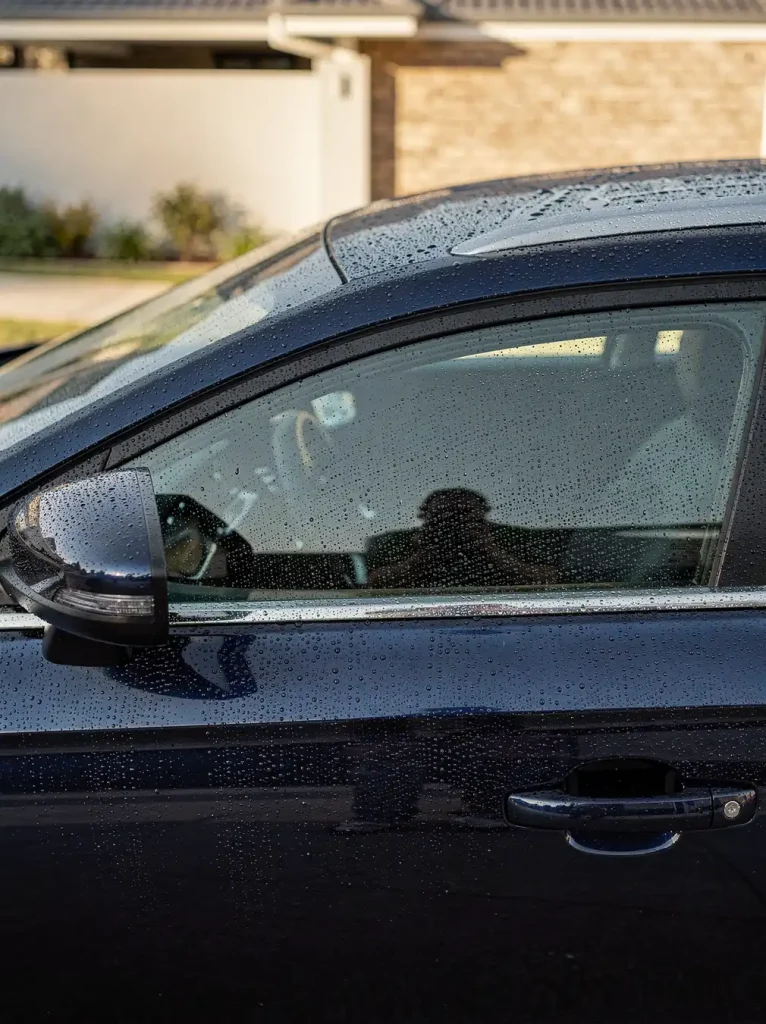 Water beads on glossy swirl-free car paint after detailing in O'Connor.