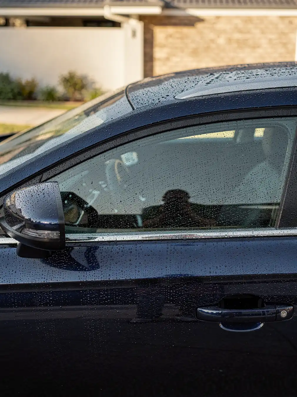 Water beads on glossy swirl-free car paint after detailing in O'Connor.