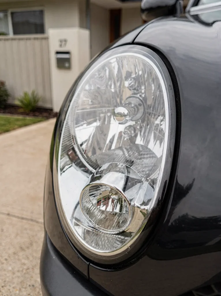 Crystal-clear restored car headlight lens with sharp chrome reflectors after O'Connor detailing.