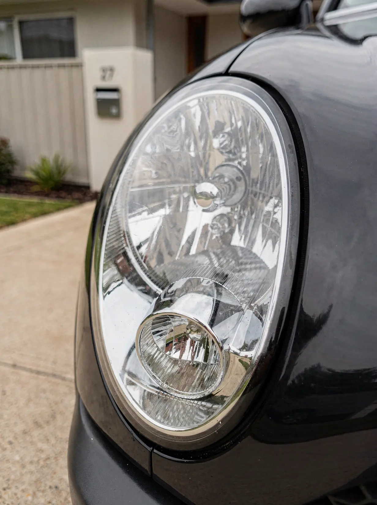 Crystal-clear restored car headlight lens with sharp chrome reflectors after O'Connor detailing.